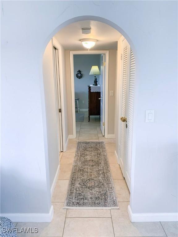 13511 Stratford Place Cir Unit 305, Fort Myers, FL 33919 - hall with light tile patterned floors, arched walkways, and baseboards
