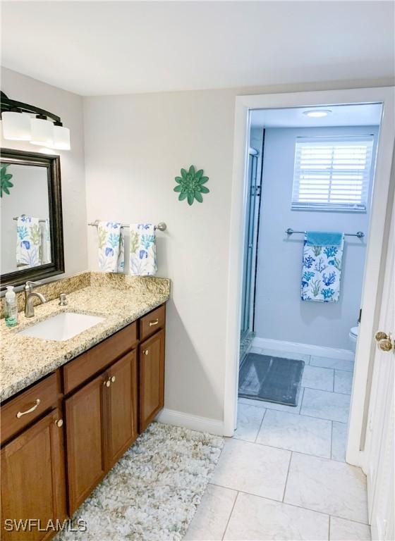 13511 Stratford Place Cir Unit 305, Fort Myers, FL 33919 - bathroom featuring vanity, a shower stall, toilet, baseboards, and tile patterned floors