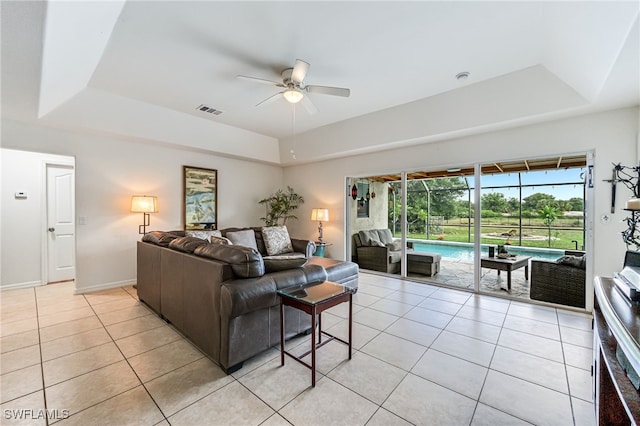 4665 47th Ave NE, Naples, FL 34120 - living room featuring a ceiling fan, a tray ceiling, light tile patterned flooring, and baseboards