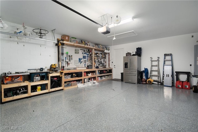 42530 Atlas Dr, Punta Gorda, FL 33982 - garage featuring a workshop area, stainless steel fridge with ice dispenser, and a garage door opener