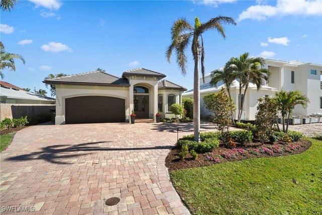 10340 Vanderbilt Dr, Naples, FL 34108 - mediterranean / spanish-style house featuring an attached garage, decorative driveway, stucco siding, and a tiled roof