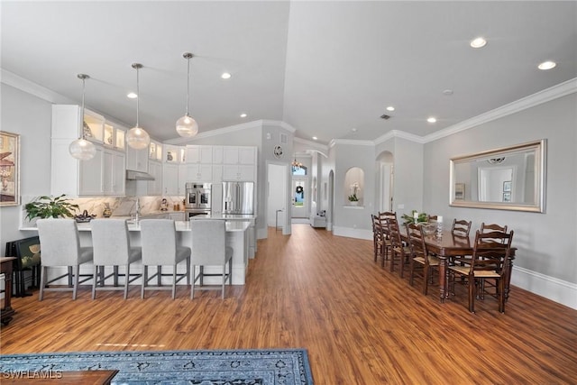 10340 Vanderbilt Dr, Naples, FL 34108 - kitchen featuring arched walkways, a peninsula, wood finished floors, a kitchen bar, and glass insert cabinets