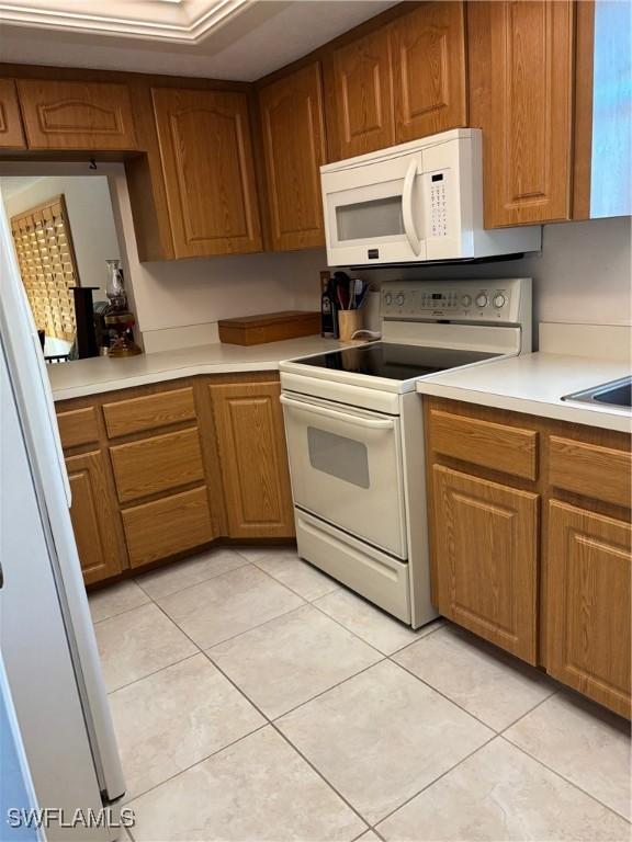 4210 SE 19th Ave Unit 2J, Cape Coral, FL 33904 - kitchen with white appliances, brown cabinets, light countertops, and light tile patterned floors