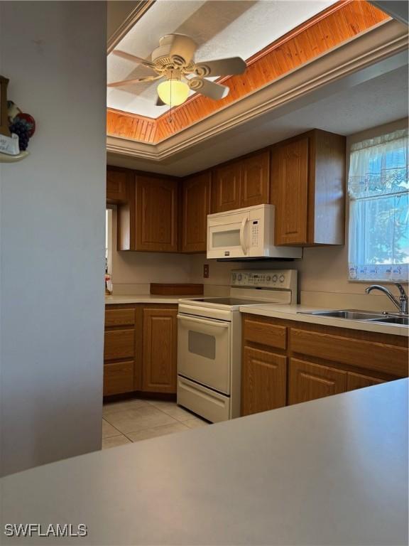 4210 SE 19th Ave Unit 2J, Cape Coral, FL 33904 - kitchen with white appliances, a sink, light tile patterned flooring, brown cabinets, and light countertops