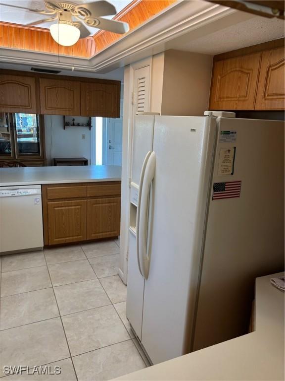 4210 SE 19th Ave Unit 2J, Cape Coral, FL 33904 - kitchen featuring white appliances, light tile patterned flooring, light countertops, a ceiling fan, and brown cabinetry