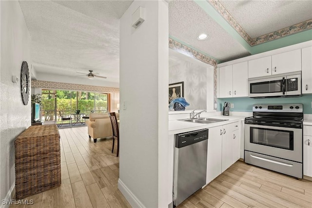 1044 Woodshire Ln Unit B102, Naples, FL 34105 - kitchen with stainless steel appliances, a textured ceiling, a sink, light wood-type flooring, and light countertops