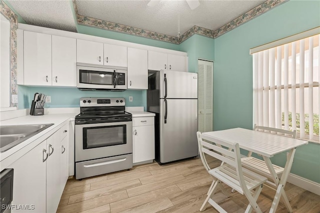 1044 Woodshire Ln Unit B102, Naples, FL 34105 - kitchen with appliances with stainless steel finishes, light wood finished floors, white cabinets, a textured ceiling, and light countertops