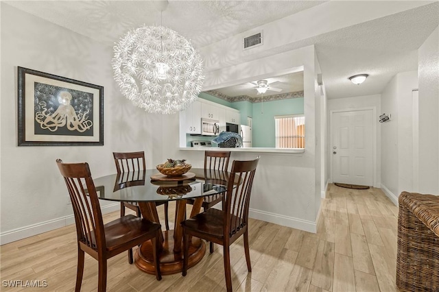 1044 Woodshire Ln Unit B102, Naples, FL 34105 - dining space featuring light wood-style floors, baseboards, a textured ceiling, a chandelier, and a ceiling fan