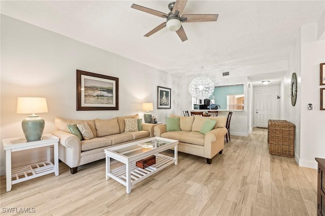 1044 Woodshire Ln Unit B102, Naples, FL 34105 - living room featuring a ceiling fan, light wood-style floors, a chandelier, baseboards, and a textured ceiling