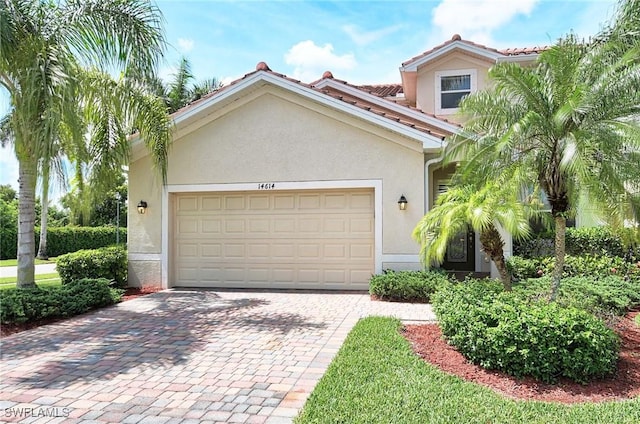 14614 Fern Lake Ct, Naples, FL 34114 - view of front of home featuring stucco siding, decorative driveway, an attached garage, and a tiled roof