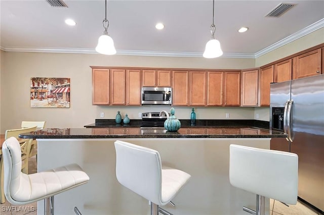 14614 Fern Lake Ct, Naples, FL 34114 - kitchen featuring stainless steel appliances, brown cabinets, crown molding, a kitchen breakfast bar, and decorative light fixtures