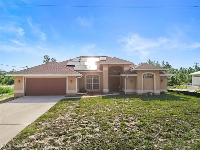 718 Willard Ave, Lehigh Acres, FL 33972 - view of front facade with a garage, concrete driveway, roof mounted solar panels, and stucco siding