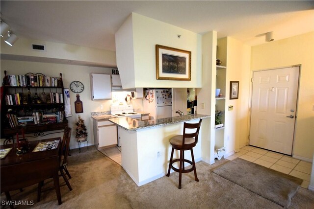 6481 Aragon Way Unit 205, Fort Myers, FL 33966 - kitchen featuring freestanding refrigerator, stove, a peninsula, stone countertops, and white cabinets
