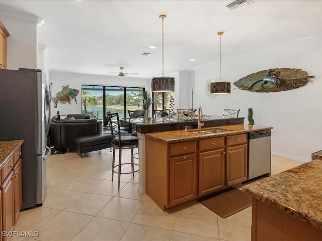 3913 Sapphire Way, Naples, FL 34114 - kitchen featuring a sink, stainless steel appliances, open floor plan, brown cabinetry, and an island with sink