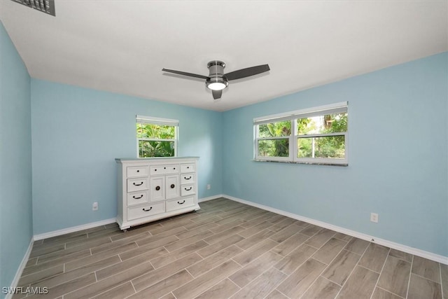 13951 Rod And Gun Club Rd, Fort Myers, FL 33913 - unfurnished bedroom featuring baseboards, wood finished floors, multiple windows, and a ceiling fan