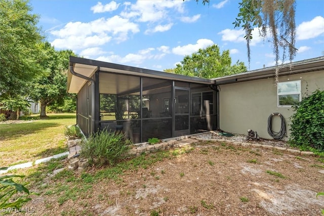 13951 Rod And Gun Club Rd, Fort Myers, FL 33913 - back of house with a sunroom, a lawn, and stucco siding