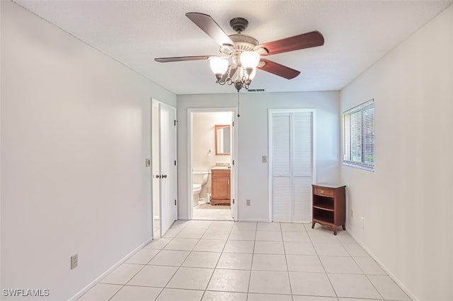 8061 S Woods Cir Unit 4, Fort Myers, FL 33919 - unfurnished bedroom featuring baseboards, light tile patterned floors, a ceiling fan, ensuite bath, and a closet