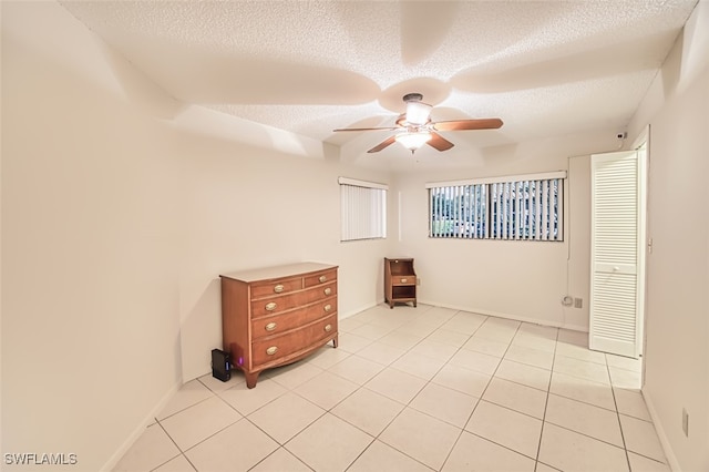 8061 S Woods Cir Unit 4, Fort Myers, FL 33919 - spare room with a textured ceiling, a ceiling fan, light tile patterned floors, and baseboards