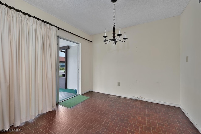 180 Cypress Way E Unit D124, Naples, FL 34110 - empty room featuring a chandelier, baseboards, and a textured ceiling