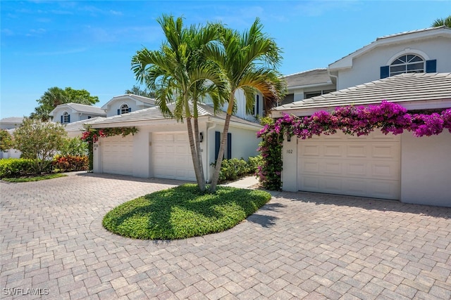 7058 Barrington Cir Unit 102, Naples, FL 34108 - view of front facade with stucco siding, decorative driveway, a tile roof, and a garage