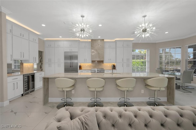 2722 Olde Cypress Dr, Naples, FL 34119 - kitchen featuring beverage cooler, built in refrigerator, wall chimney exhaust hood, a chandelier, and ornamental molding