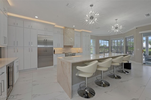 2722 Olde Cypress Dr, Naples, FL 34119 - kitchen with stainless steel appliances, light marble finish flooring, baseboards, crown molding, and a chandelier