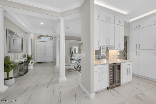 2722 Olde Cypress Dr, Naples, FL 34119 - kitchen with wine cooler, decorative columns, light marble finish floors, baseboards, and crown molding