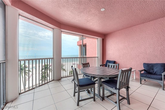 190 Estero Blvd Unit 303, Fort Myers Beach, FL 33931 - dining room with a textured wall, view of water and beach, a textured ceiling, and light tile patterned flooring