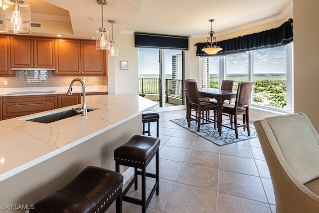 1050 Borghese Ln Unit 1101, Naples, FL 34114 - kitchen featuring ornamental molding, a sink, brown cabinets, decorative backsplash, and plenty of natural light