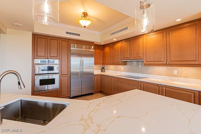 1050 Borghese Ln Unit 1101, Naples, FL 34114 - kitchen featuring appliances with stainless steel finishes, a sink, brown cabinetry, light stone countertops, and crown molding