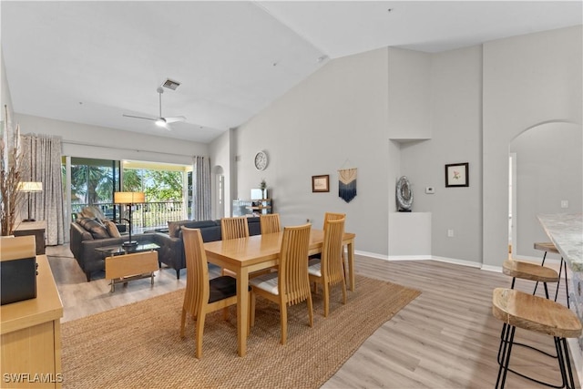 14769 Calusa Palms Dr Unit 203, Fort Myers, FL 33919 - dining space with arched walkways, light wood-style flooring, ceiling fan, baseboards, and high vaulted ceiling