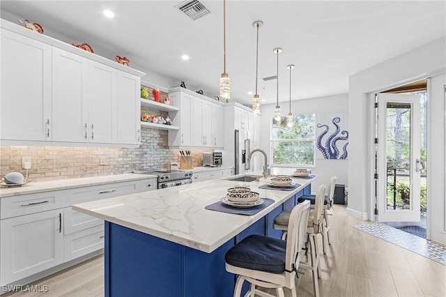 28105 Mandolin Ct Unit 214, Bonita Springs, FL 34135 - kitchen featuring a sink, appliances with stainless steel finishes, decorative backsplash, open shelves, and a center island with sink