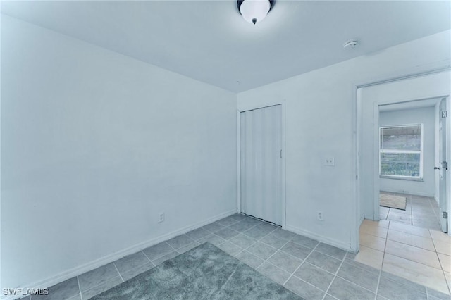 911 Medford Ave S, Lehigh Acres, FL 33974 - unfurnished bedroom featuring light tile patterned floors, a closet, and baseboards