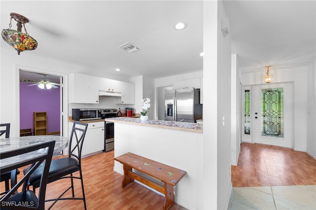 911 Medford Ave S, Lehigh Acres, FL 33974 - kitchen featuring stainless steel appliances, white cabinetry, under cabinet range hood, recessed lighting, and light wood finished floors