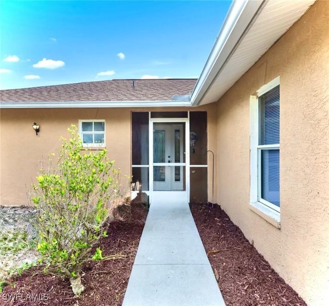 911 Medford Ave S, Lehigh Acres, FL 33974 - view of exterior entry with stucco siding and a shingled roof