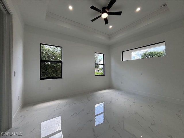 empty room featuring a raised ceiling, crown molding, recessed lighting, light marble finish flooring, and a ceiling fan