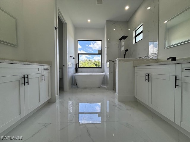 full bathroom featuring marble tiled flooring, vanity, a freestanding tub, and recessed lighting