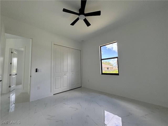 unfurnished bedroom with marble finish flooring, a closet, and a ceiling fan