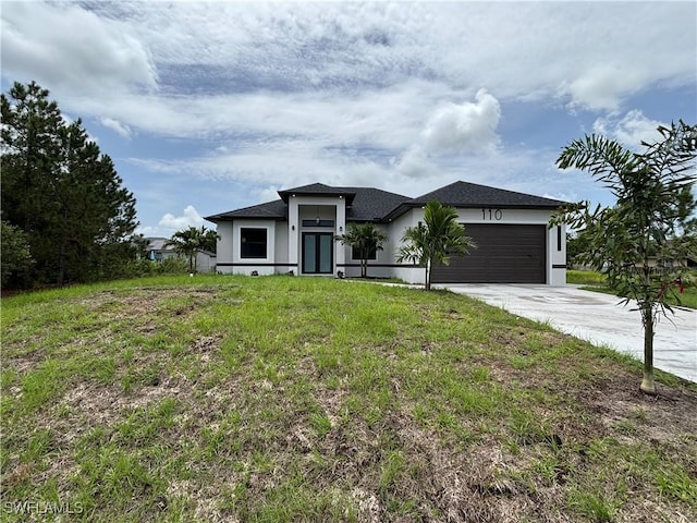 prairie-style home featuring concrete driveway, a garage, stucco siding, and a front yard