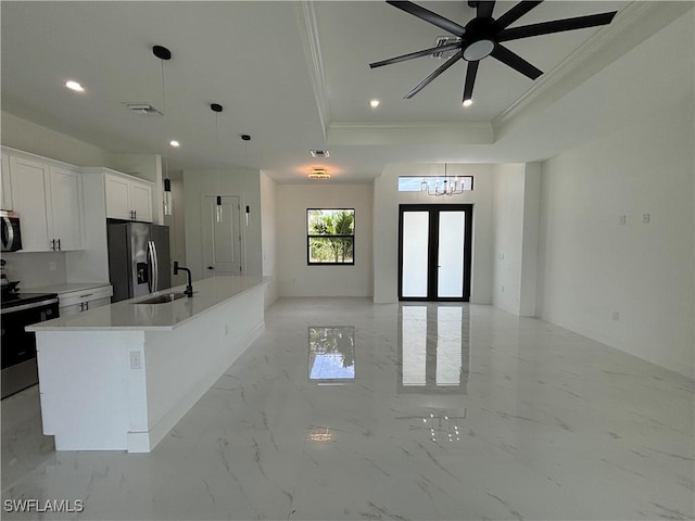 kitchen featuring stainless steel appliances, crown molding, a tray ceiling, a center island with sink, and open floor plan