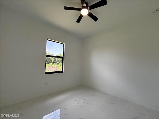 unfurnished room with marble finish floors and a ceiling fan