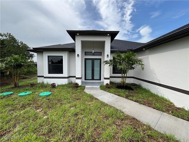 view of front of home featuring stucco siding, french doors, and a front yard