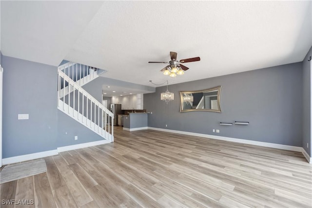 5831 Cove Cir Unit 6, Naples, FL 34119 - unfurnished living room featuring stairs, ceiling fan, baseboards, light wood-type flooring, and a chandelier