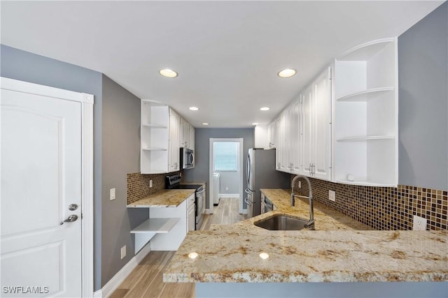 5831 Cove Cir Unit 6, Naples, FL 34119 - kitchen with open shelves, appliances with stainless steel finishes, a sink, white cabinets, and light stone counters