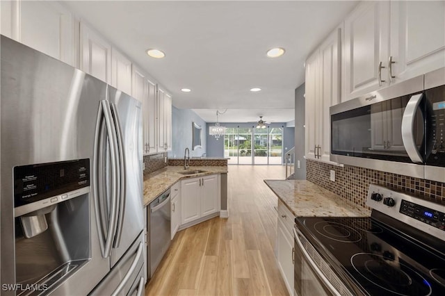 5831 Cove Cir Unit 6, Naples, FL 34119 - kitchen featuring stainless steel appliances, a sink, light wood finished floors, a peninsula, and white cabinetry