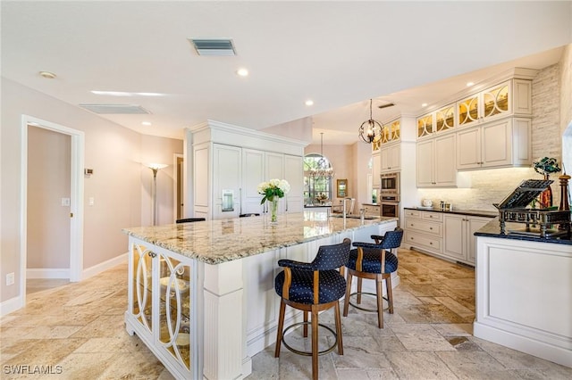 8241 Glenfinnan Cir, Fort Myers, FL 33912 - kitchen featuring stone tile flooring, a chandelier, appliances with stainless steel finishes, glass insert cabinets, and recessed lighting