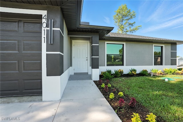 4011 7th St SW, Lehigh Acres, FL 33976 - doorway to property with stucco siding, an attached garage, and a lawn