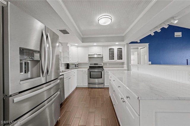 1311 SE 11th St, Cape Coral, FL 33990 - kitchen featuring appliances with stainless steel finishes, under cabinet range hood, white cabinetry, wood finish floors, and ornamental molding