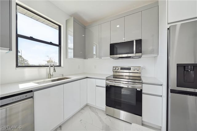 4309 NW 38th Ave, Cape Coral, FL 33993 - kitchen with appliances with stainless steel finishes, a sink, light marble finish floors, modern cabinets, and light countertops