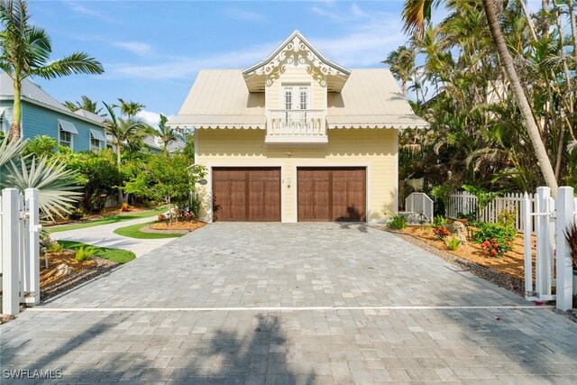15009 Binder Dr, Captiva, FL 33924 - view of front facade featuring a balcony, decorative driveway, metal roof, and a garage